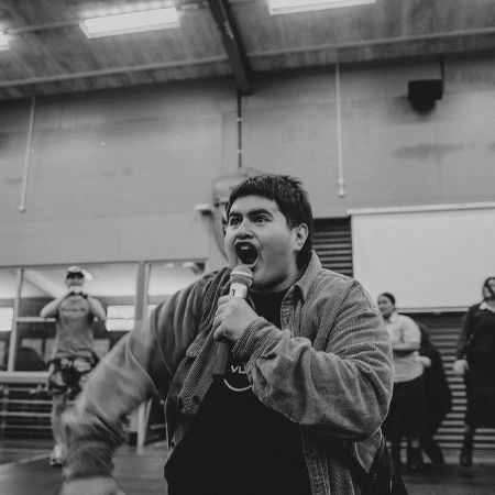 Julian Dennison is performing with his mic on the basketball court.
